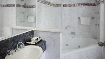 Un baño moderno con lavamanos de mármol, un espejo grande y una zona de ducha separada.