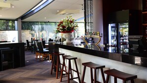 Eine moderne Bar mit einer schwarzen Arbeitsplatte, Holzstühlen und einer dekorativen Blumenvase.