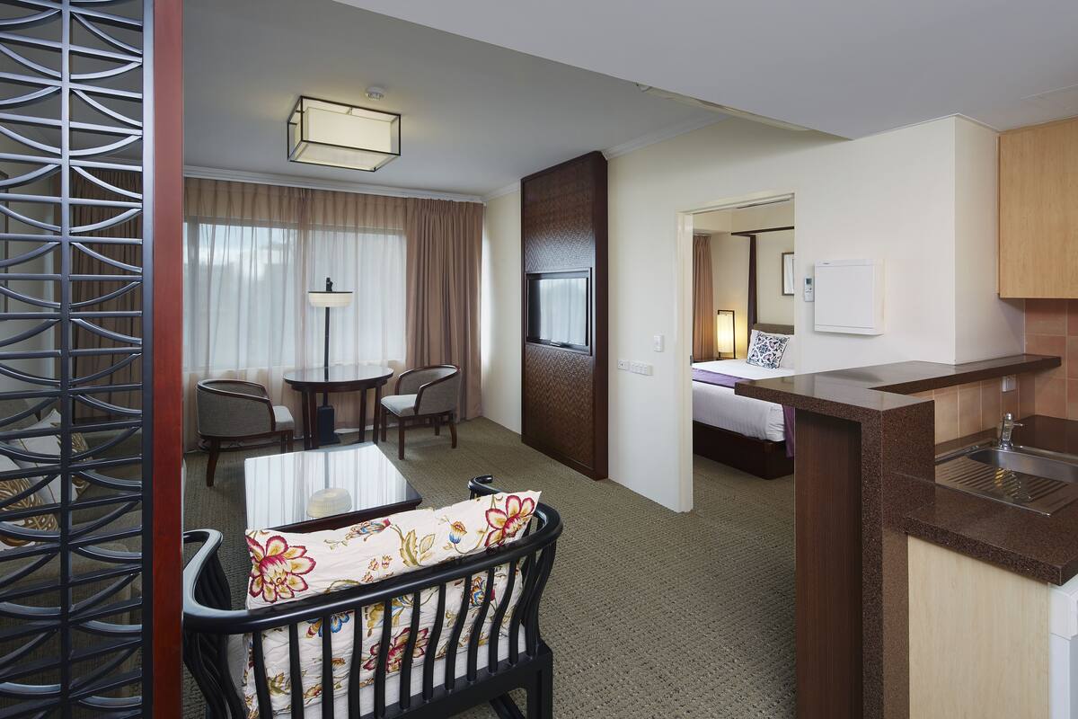 A hotel room with a dining area, a bed, a kitchenette, and a bathroom.