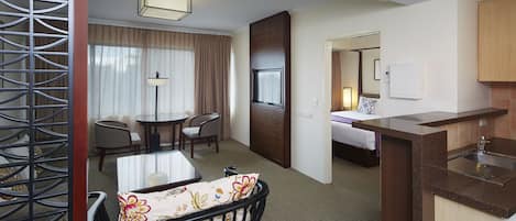 Habitación de hotel con comedor, cama, kitchenette y baño.