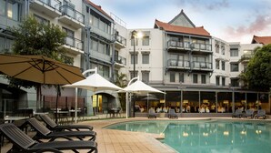 Ein Hotel mit Schwimmbad, Liegestühlen und einem Essbereich im Freien.