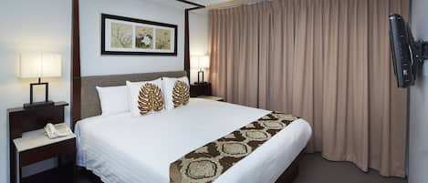 Una habitación de hotel con una cama grande, dos mesitas de noche, un teléfono, un cuadro enmarcado, un televisor y una ventana con cortinas.