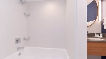 Une salle de bain moderne avec une baignoire blanche, une pomme de douche et un meuble-lavabo avec un miroir.