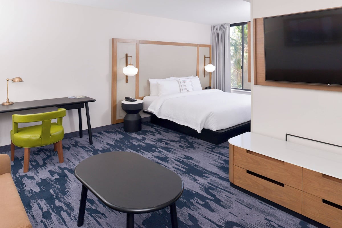 Een hotelkamer met een bed, bureau, stoel, televisie en tv-meubel.