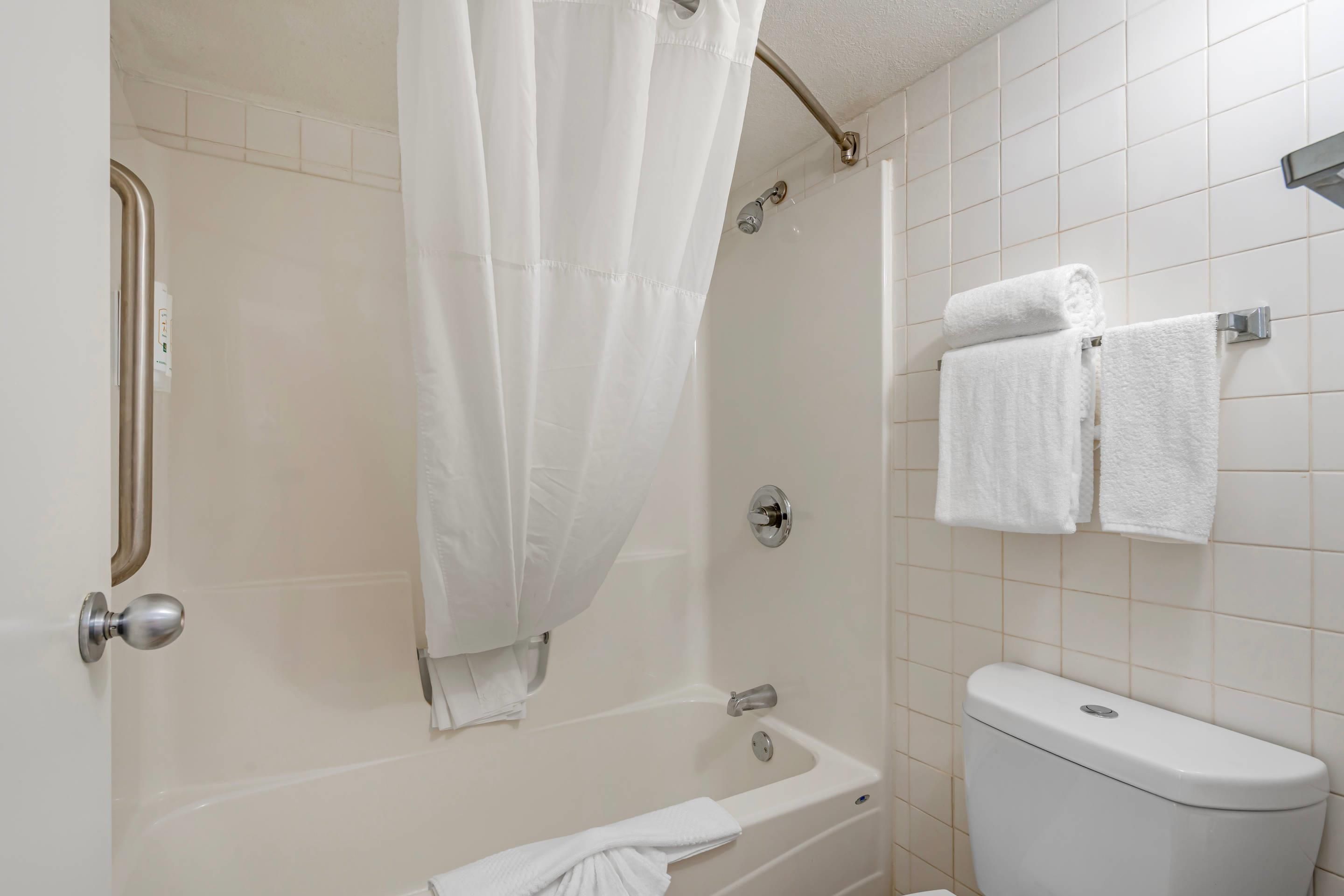 A bathroom with a bathtub, a shower curtain, a toilet, and a towel rack.