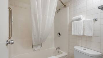 A bathroom with a bathtub, a shower curtain, a toilet, and a towel rack.