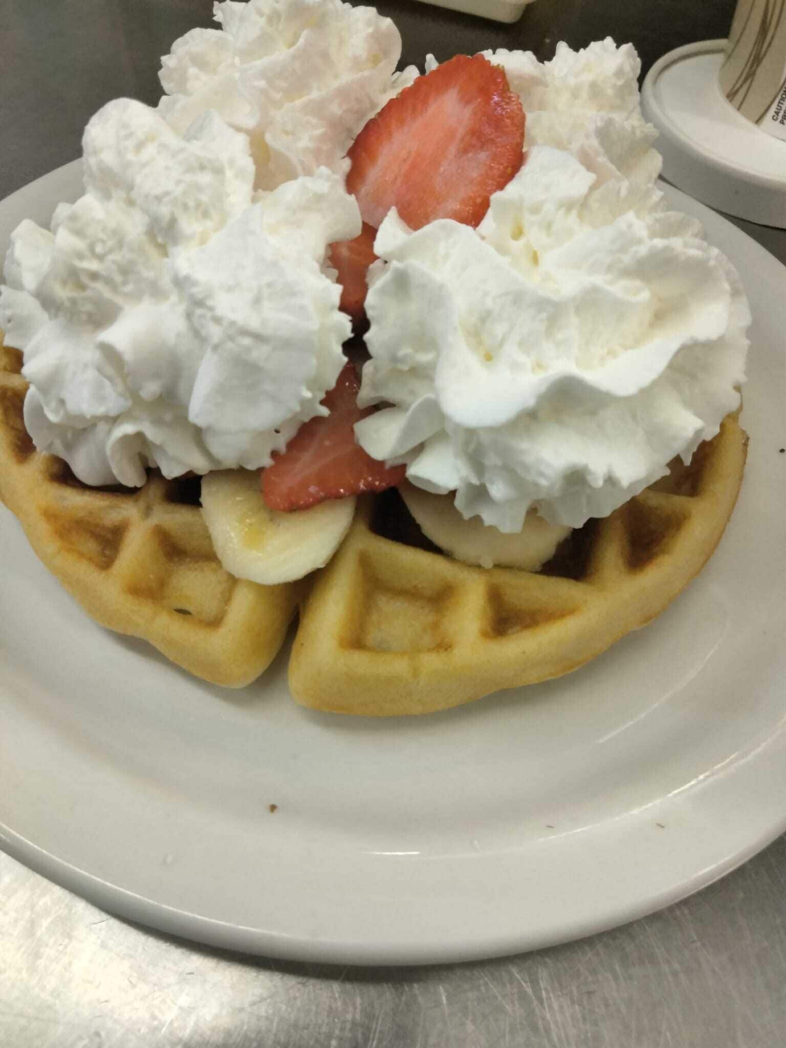 A waffle topped with whipped cream and a strawberry.