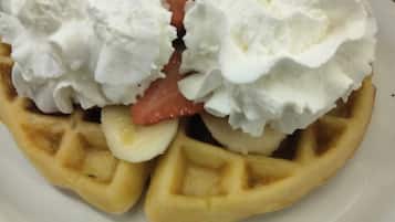 Een wafel met slagroom en een aardbei.
