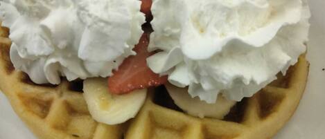 A waffle topped with whipped cream and a strawberry.