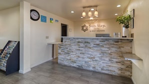 Zona de recepción de un hotel con un mostrador de piedra, un reloj y un cartel que dice "SureStay Hotel by Best Western".