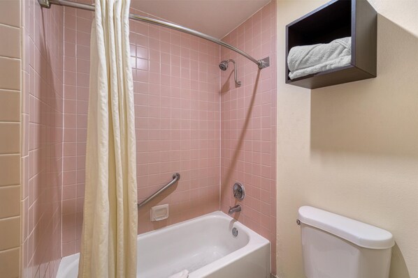 A bathroom with a bathtub, a shower curtain, a towel rack, and a toilet.