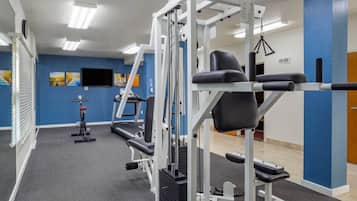 Een sportschool met trainingsapparatuur, een loopband en een televisie aan de muur.