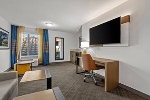 A hotel room with a desk, chair, TV, and a view of the outdoors. - Comfort Inn South San Jose / Morgan Hill (Morgan Hill)