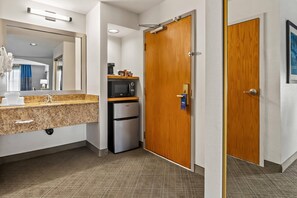A hotel bathroom with a sink, mirror, and a refrigerator. - Comfort Inn South San Jose / Morgan Hill (Morgan Hill)