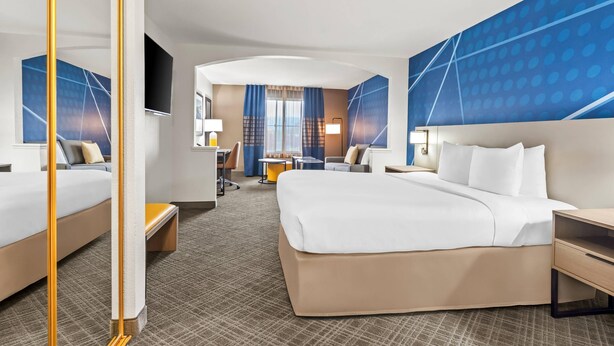 A hotel room with two beds, a desk, a chair, a TV, and a large window with curtains. - Comfort Inn South San Jose / Morgan Hill (Morgan Hill)