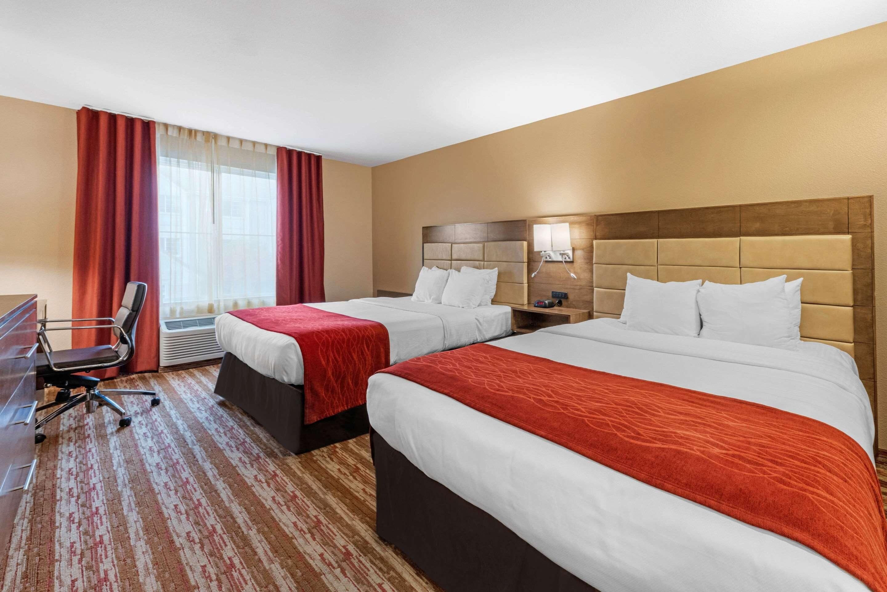 Habitación de hotel con dos camas, un escritorio y una silla.