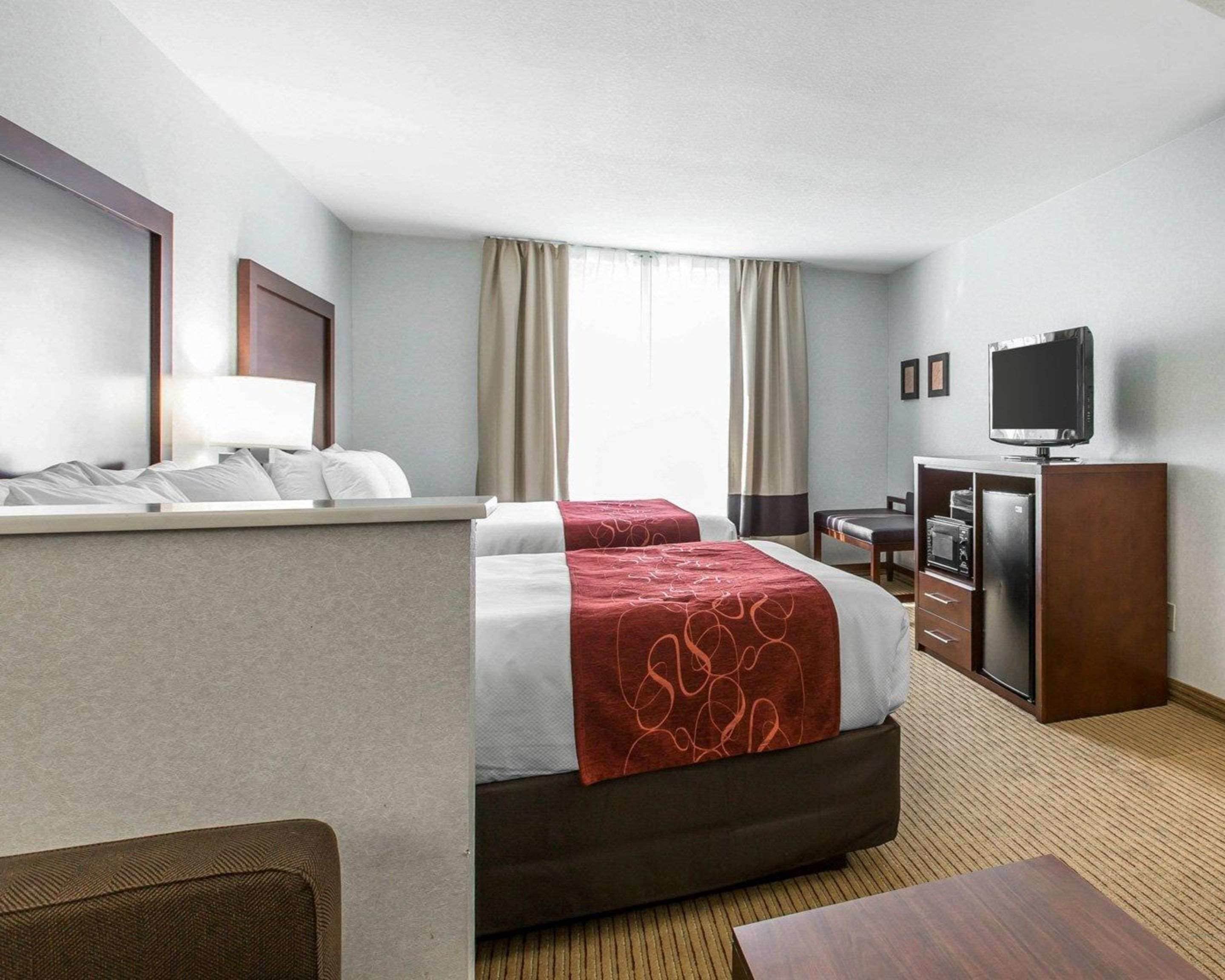 Ein Hotelzimmer mit Bett, Schreibtisch, Fernseher und Minibar.