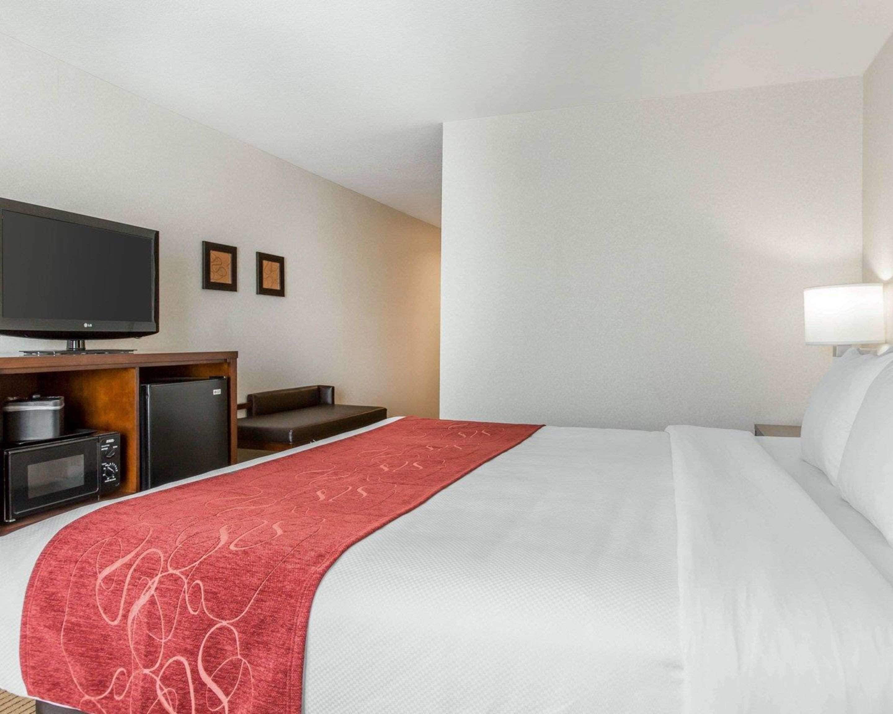 Hotellihuone, jossa on sänky, televisio, mikroaaltouuni ja pieni jääkaappi.
