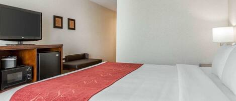 A hotel room with a bed, a TV, a microwave, and a small refrigerator.