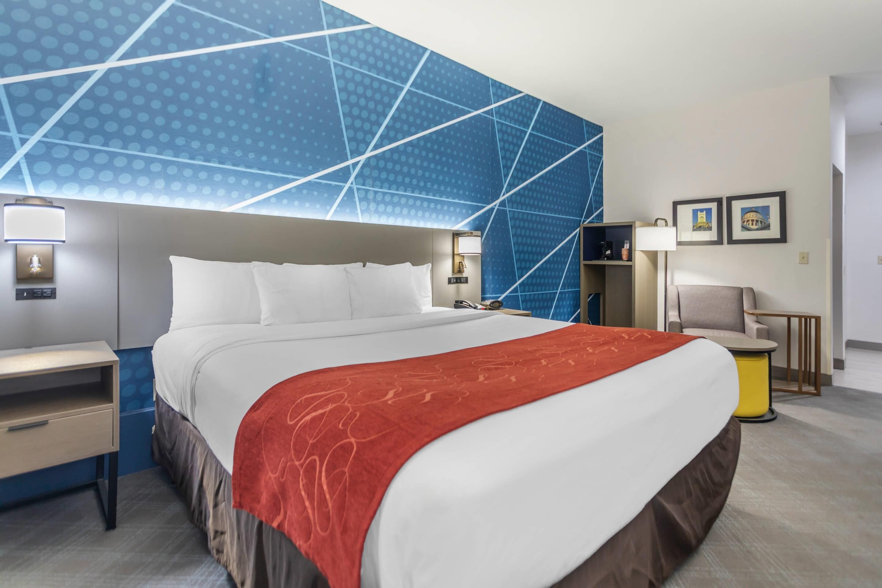 Une chambre d’hôtel moderne avec un grand lit, une table de chevet, un bureau et une chaise.