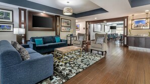 A spacious living area with a large sofa, a coffee table, and a dining area with chairs and a table. - Comfort Suites Downtown Sacramento (Sacramento)