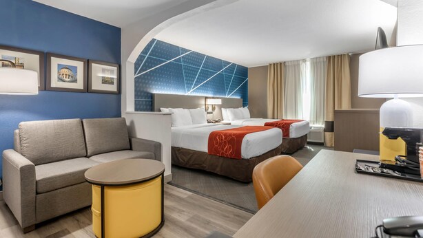 A hotel room with a sofa, two beds, a desk, and a lamp. - Comfort Suites Downtown Sacramento (Sacramento)
