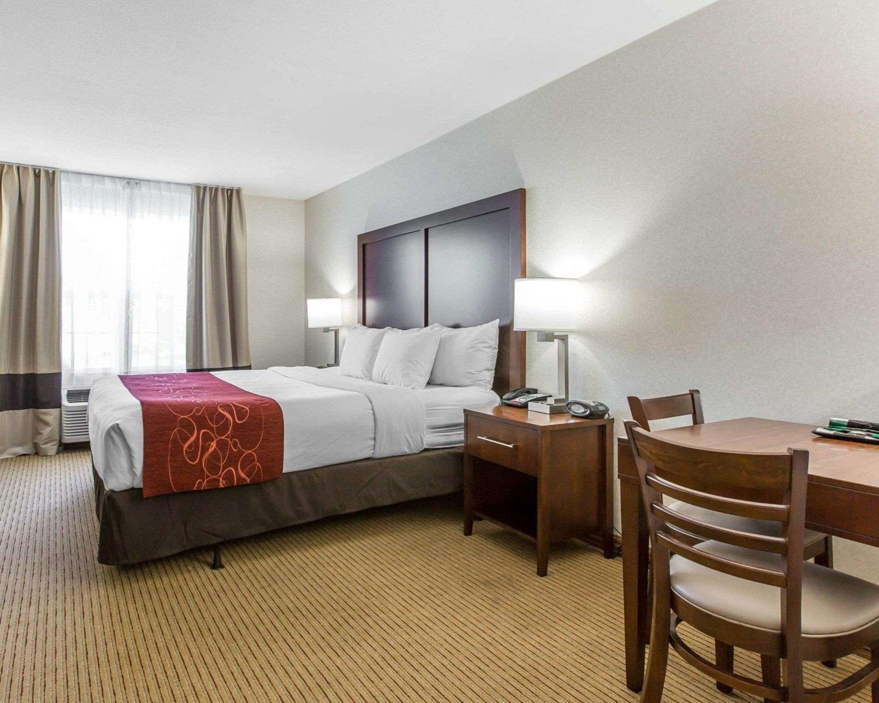 A hotel room with a bed, bedside tables, a desk, and a chair.