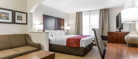 Una habitación de hotel con cama, sofá, escritorio, lámpara y televisor.