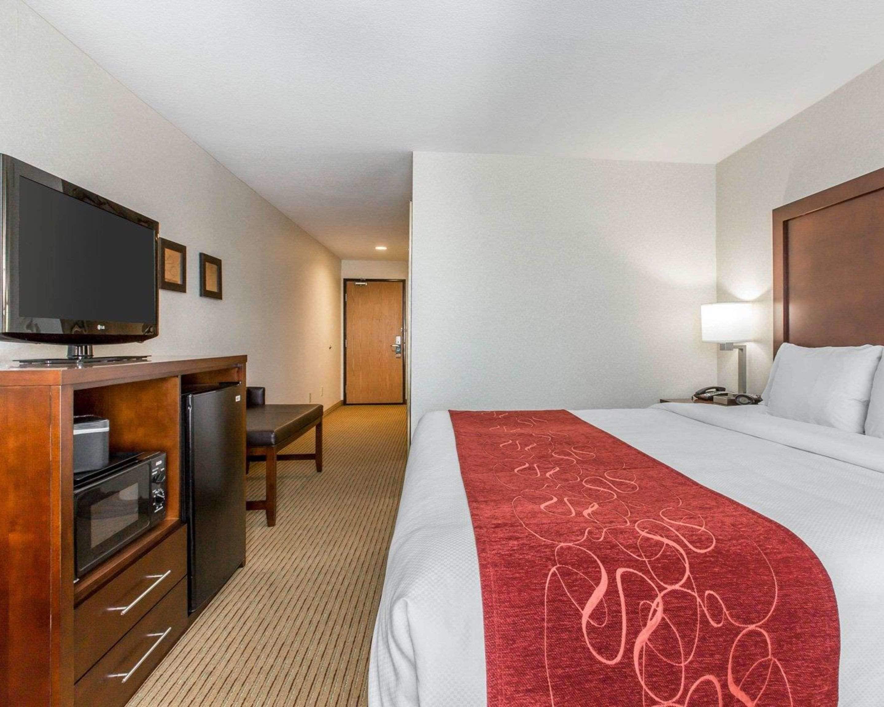 A hotel room with a bed, a TV, a desk, and a microwave.