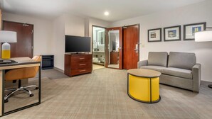 A hotel room with a desk, chair, sofa, television, and a small yellow table. - Comfort Suites Downtown Sacramento (Sacramento)