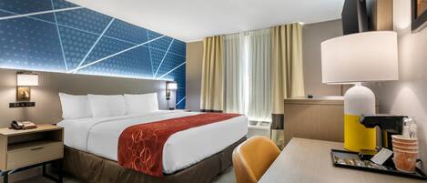 Hotelkamer met een groot bed, een bureau met lamp, een stoel, een nachtkastje met telefoon en een aan de muur bevestigde televisie.