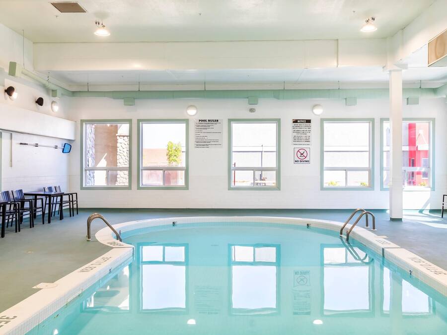 An indoor swimming pool with clear pool rules and no diving signs.