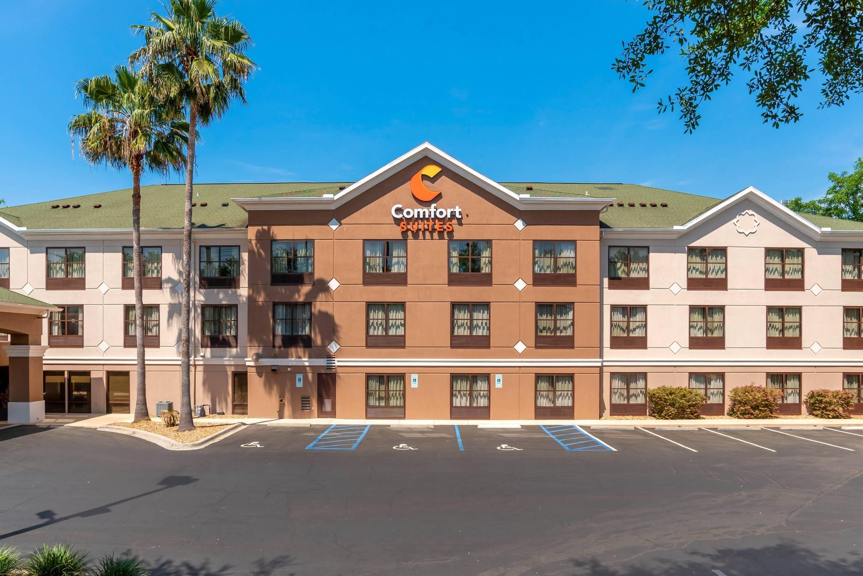 Un hotel Comfort Suites con fachada simétrica, varias ventanas y estacionamiento.