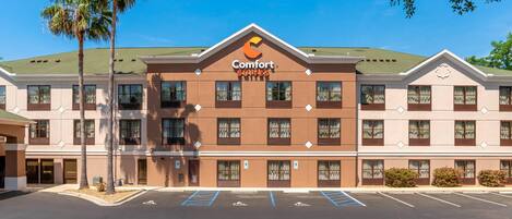 Un hotel Comfort Suites con fachada simétrica, varias ventanas y estacionamiento.