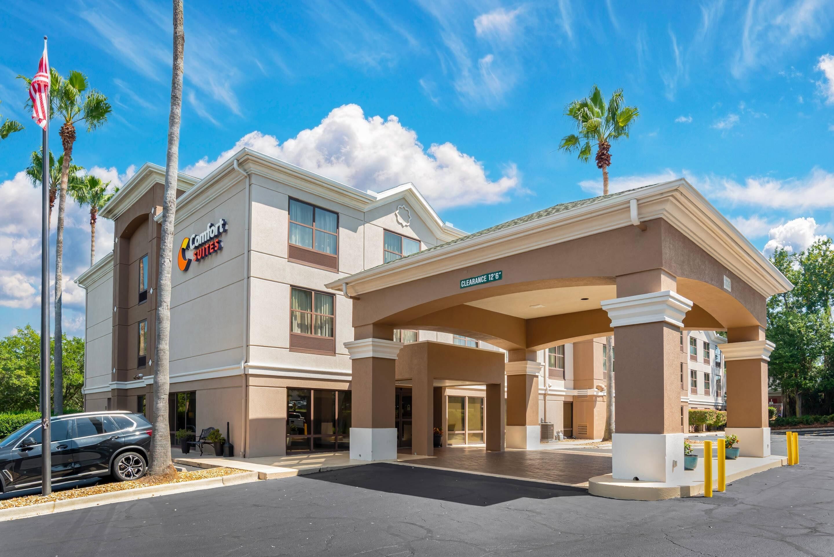 Un hôtel Comfort Suites avec une entrée bien visible, des palmiers et un parking.