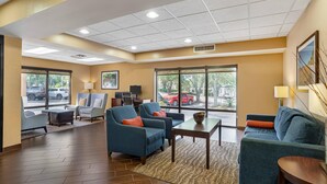 Un hall d’hôtel avec des sièges, un comptoir d’accueil, de grandes fenêtres et une vue sur l’extérieur.