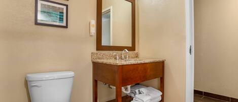 A bathroom with a toilet, a sink with a mirror, and a towel rack.