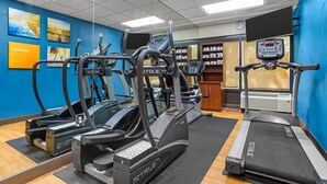 Une salle de sport équipée de tapis de course, de vélos elliptiques et d’une machine de musculation.