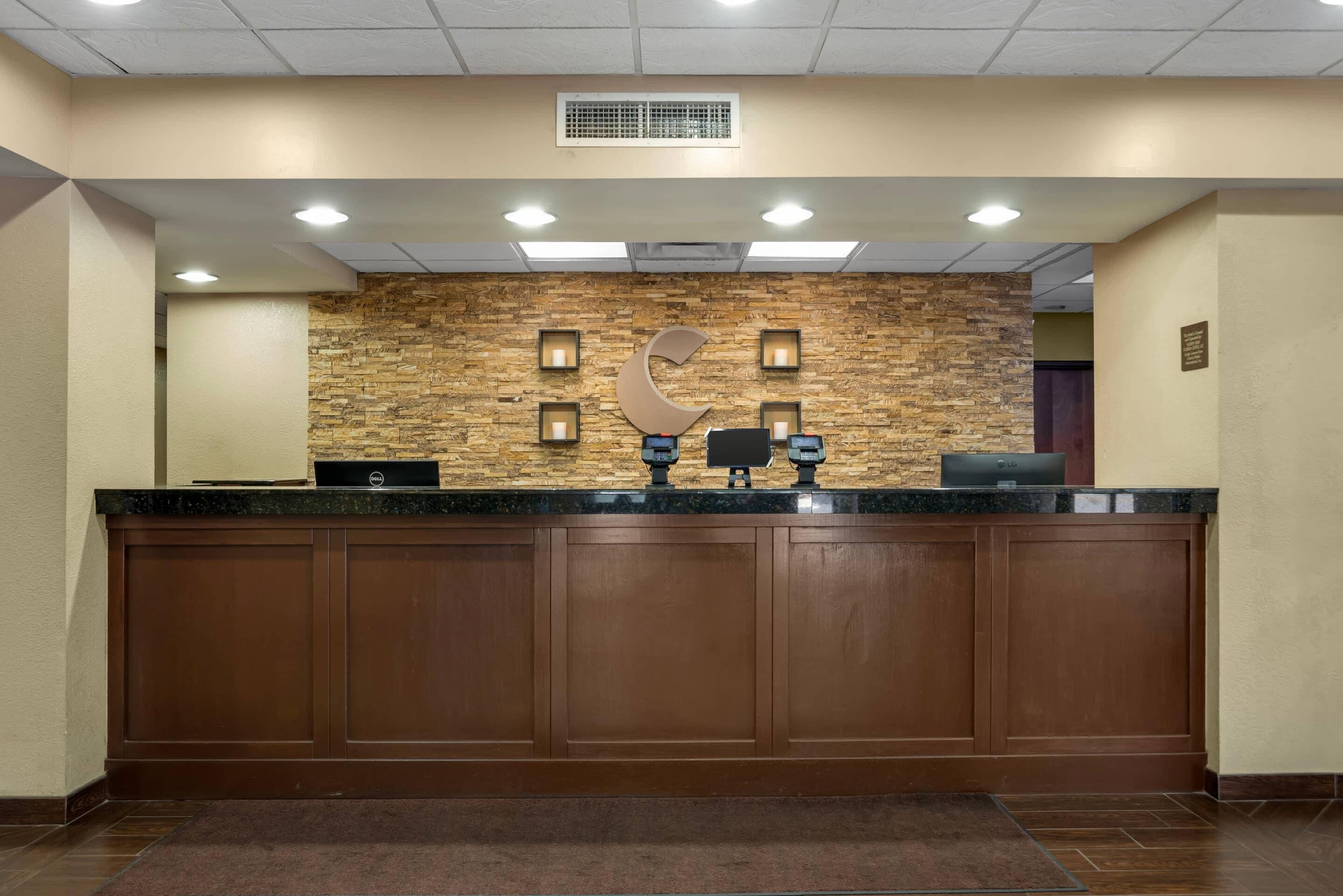 A reception desk with a stone wall backdrop, recessed lighting, and a dark wood finish.