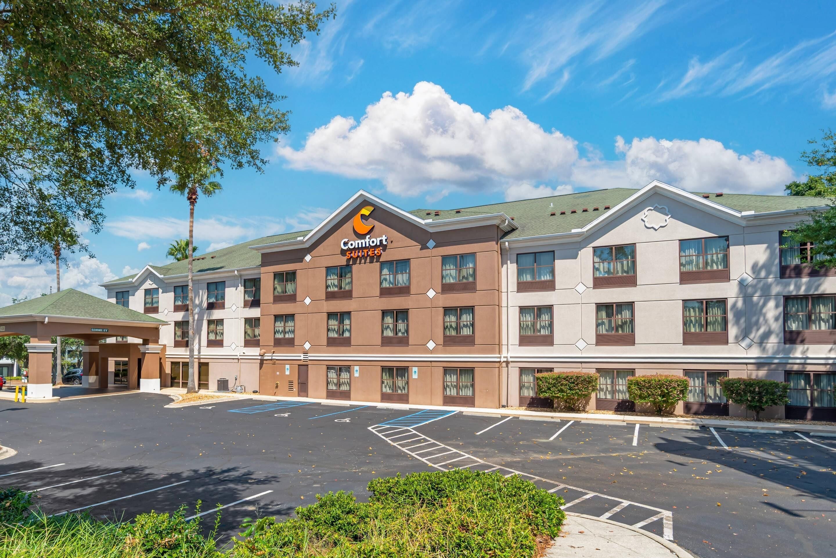 A Comfort Suites hotel with a parking lot, multiple floors, and a green roof.