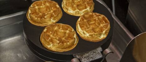 Four waffles cooking on a griddle.