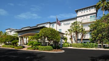 Un hotel Marriott Fairfield con una grande bandiera americana, un ingresso coperto e un paesaggio curato.