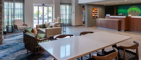 A spacious lobby with a reception desk, seating area, and a view of the outdoors.
