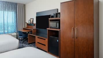 A hotel room with two beds, a desk, a television, a microwave, and a wardrobe.