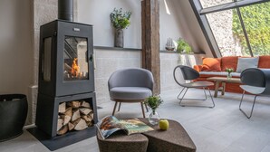 A cozy room with a wood-burning stove, comfortable seating, and a view through a large window. - Hotel Saint Nicolas (La Rochelle)