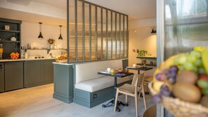 A modern kitchen with a built-in bench, a dining area with a table and chairs, and a large window with a view. - Hotel Saint Nicolas (La Rochelle)
