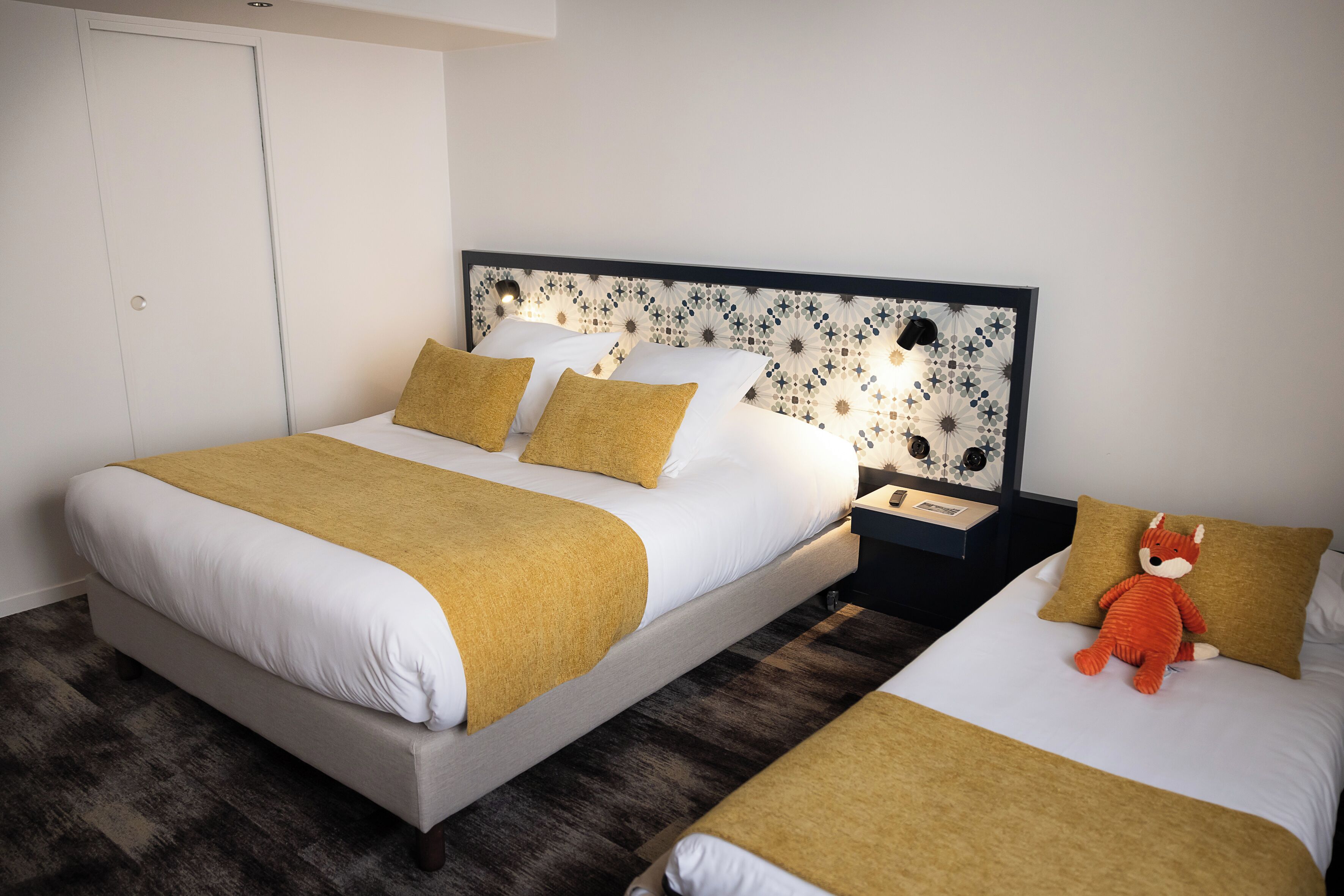 A double bed with a patterned headboard, a bedside table, and a nightstand.