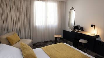 Ein Hotelzimmer mit zwei Betten, einem Schreibtisch, einem Stuhl, einem Spiegel und einer Lampe.
