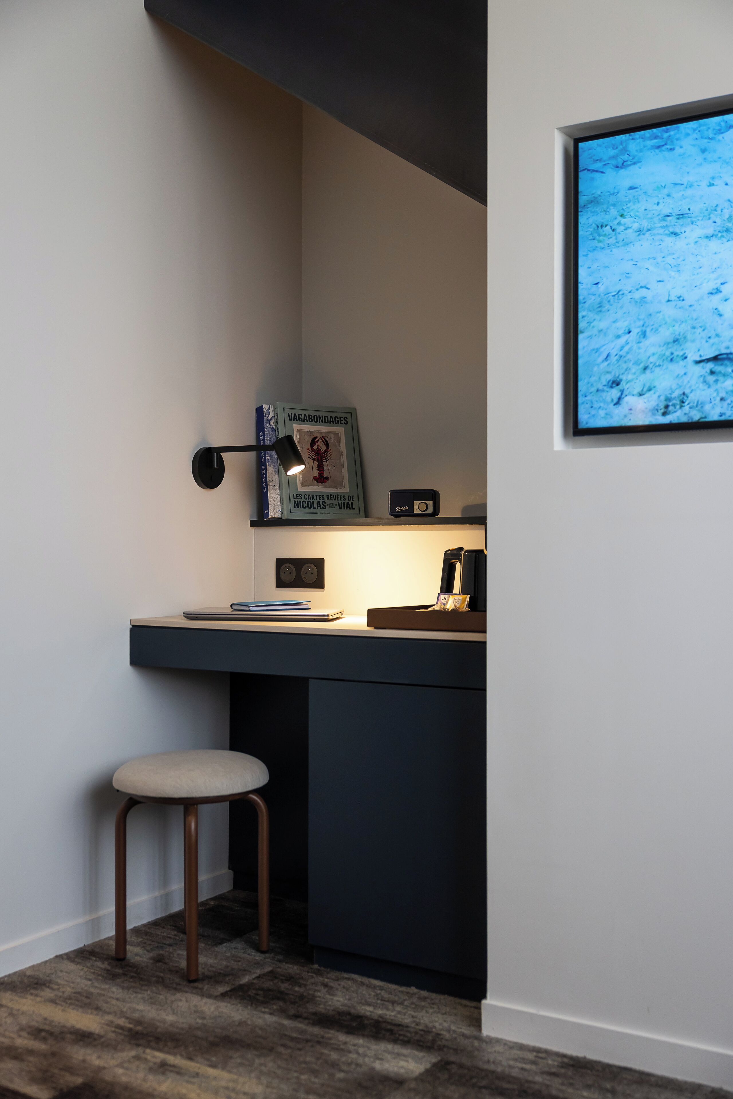 Un espace de travail moderne comprenant un bureau, une chaise et un tableau encadré accroché au mur.