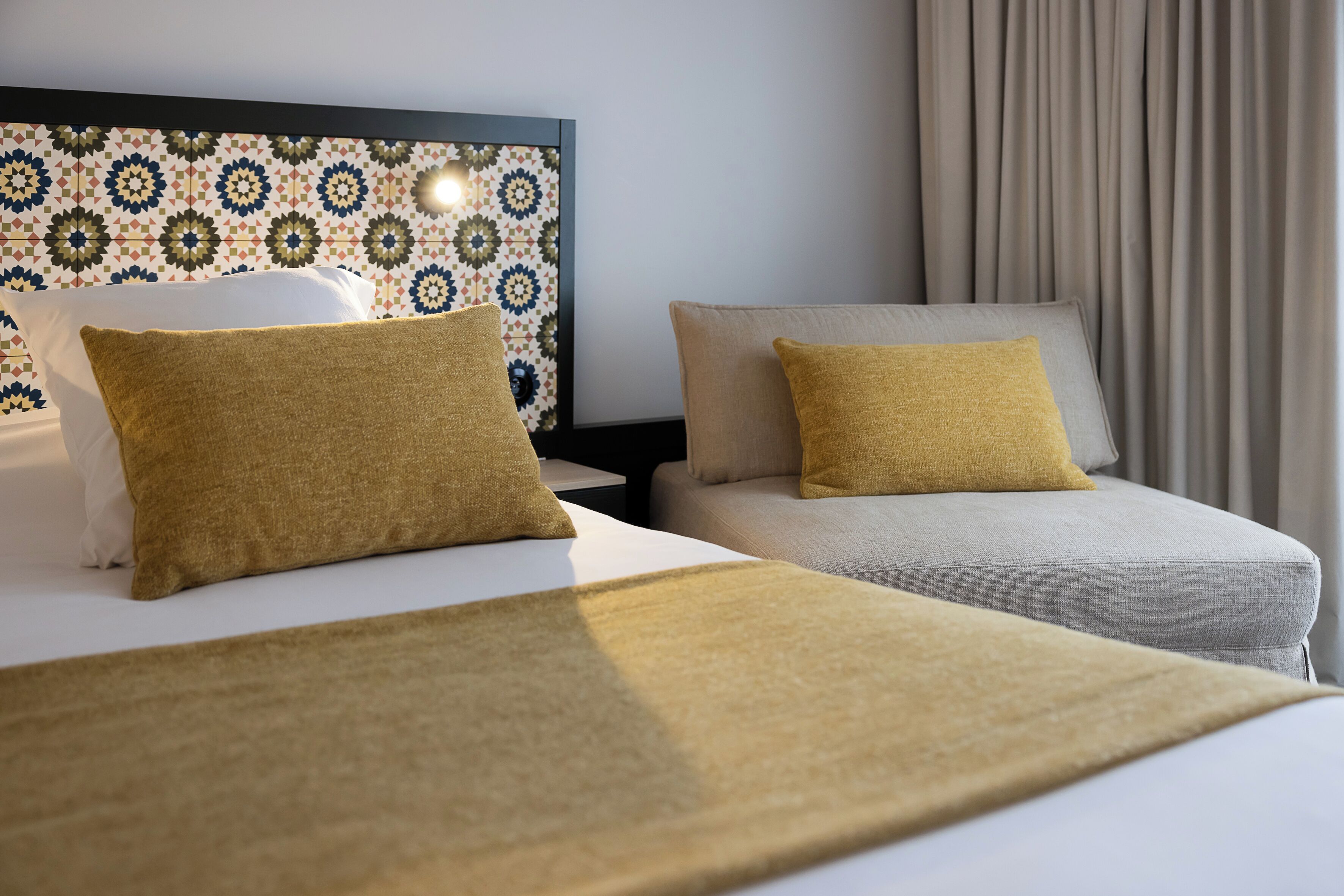 Ein Hotelzimmer mit einem Bett, zwei Sesseln und einer Wand mit Muster.